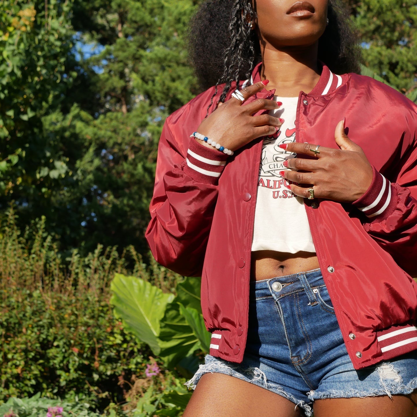 A black woman model with a red jacket showing 3 ring by Attale jewels