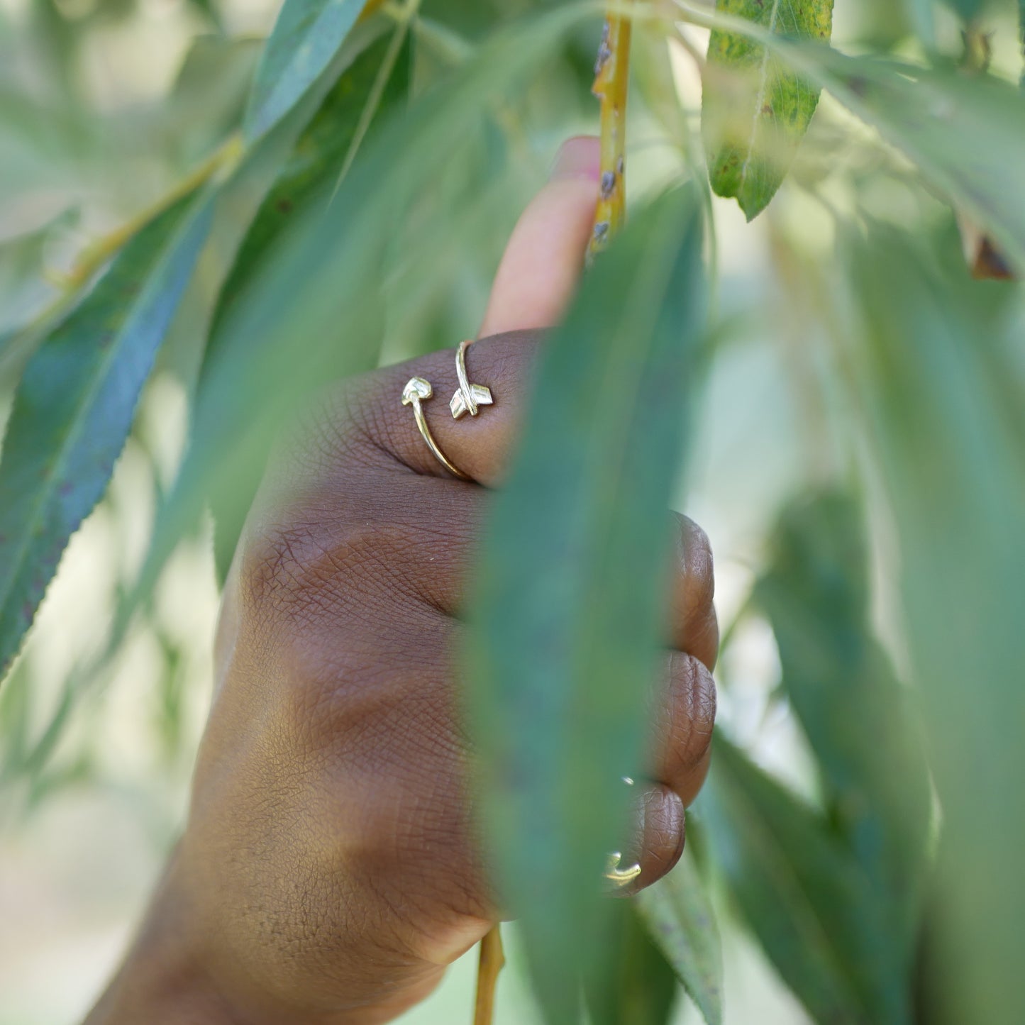 A black woman hand with a gold heart arrow ring on one of her finger