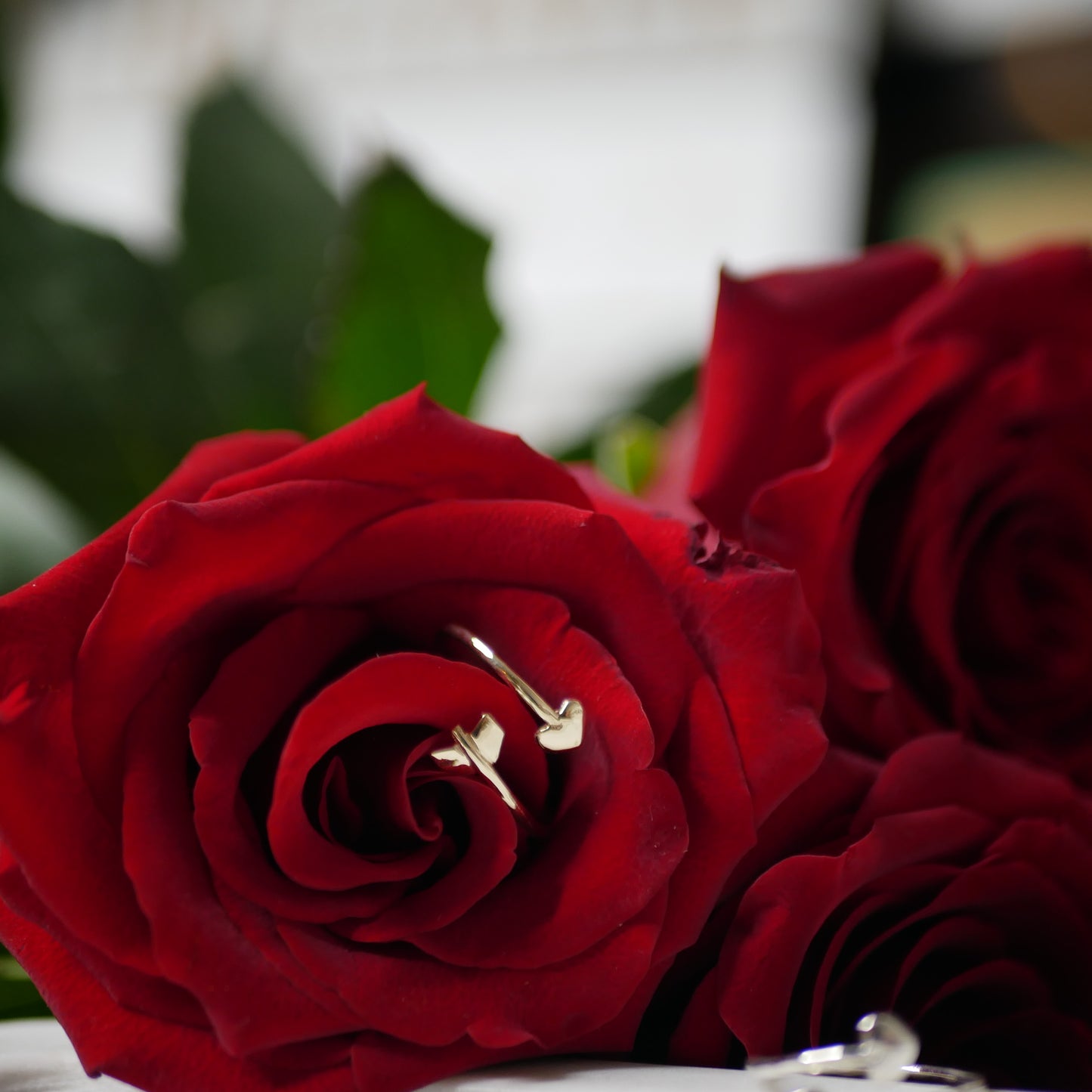 A gold heart arrow ring in one rose just beside 2 other roses