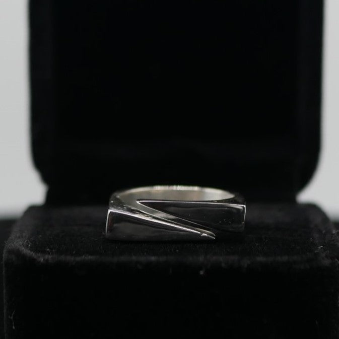 A silver pincer ring displayed in a box